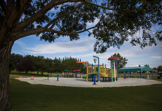 A park in the City of Brooks with trees and a playground