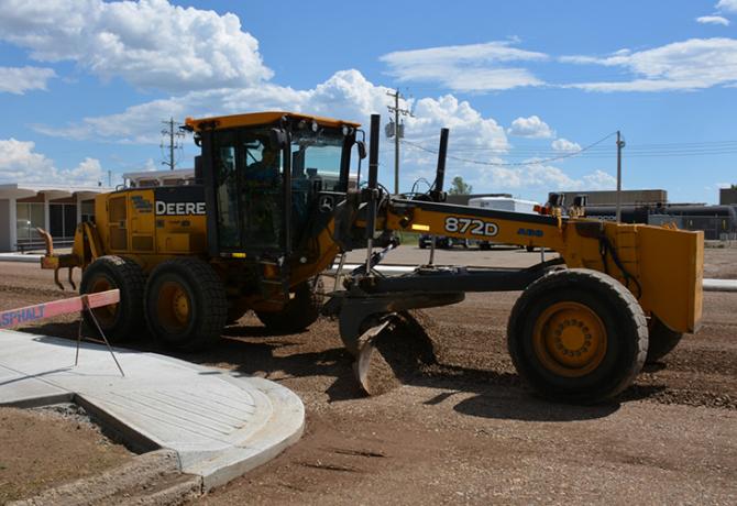 A construction vehicle laying gravel on a new road in the City of Brooks